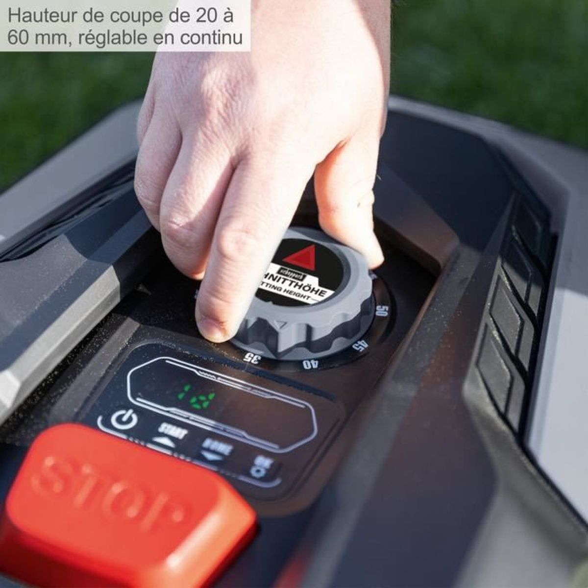 Zbliżenie osoby regulującej szare pokrętło na kosiarce. Czerwony przycisk stop.