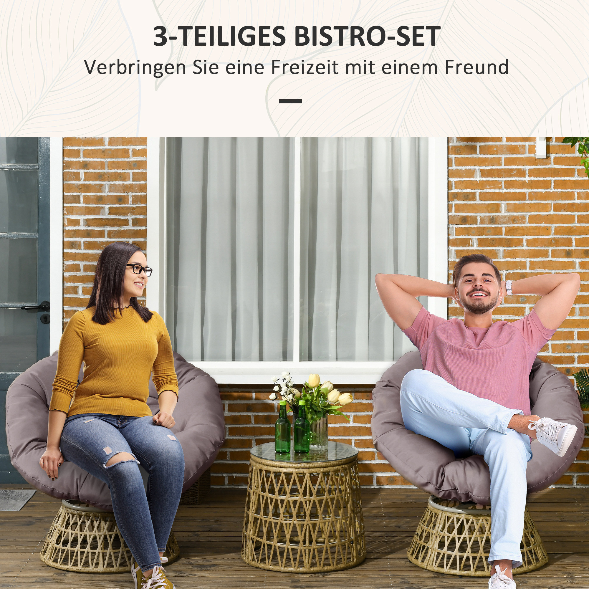 Zwei Personen sitzen in großen runden Stühlen auf einer Terrasse, ein Tisch mit Blumen dazwischen.
