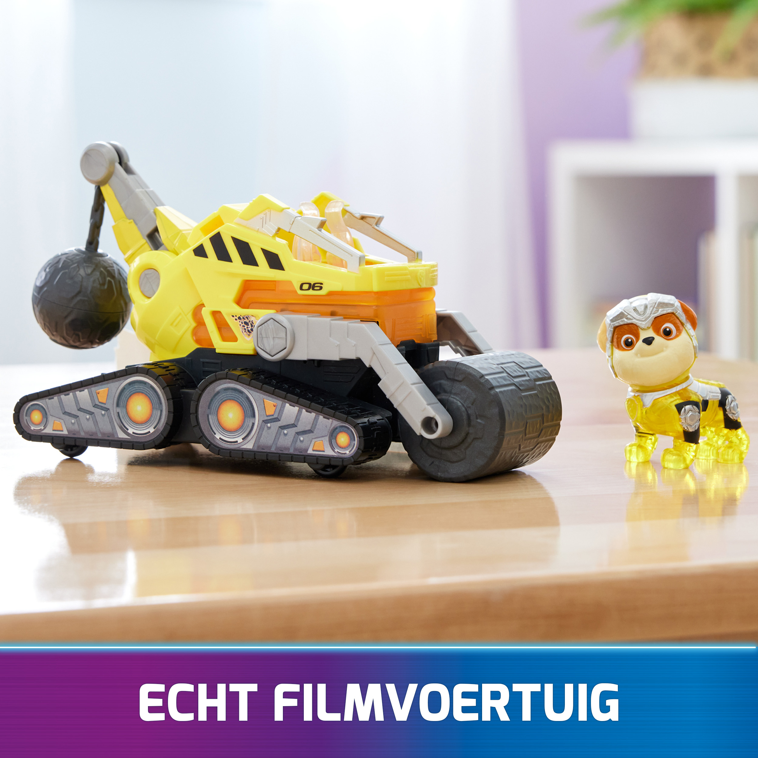 Gelber Spielzeug-Truck mit Hundefigur und einer weiteren Figur. Text: Echtes Filmfahrzeug. Der Truck steht auf einem Tisch.