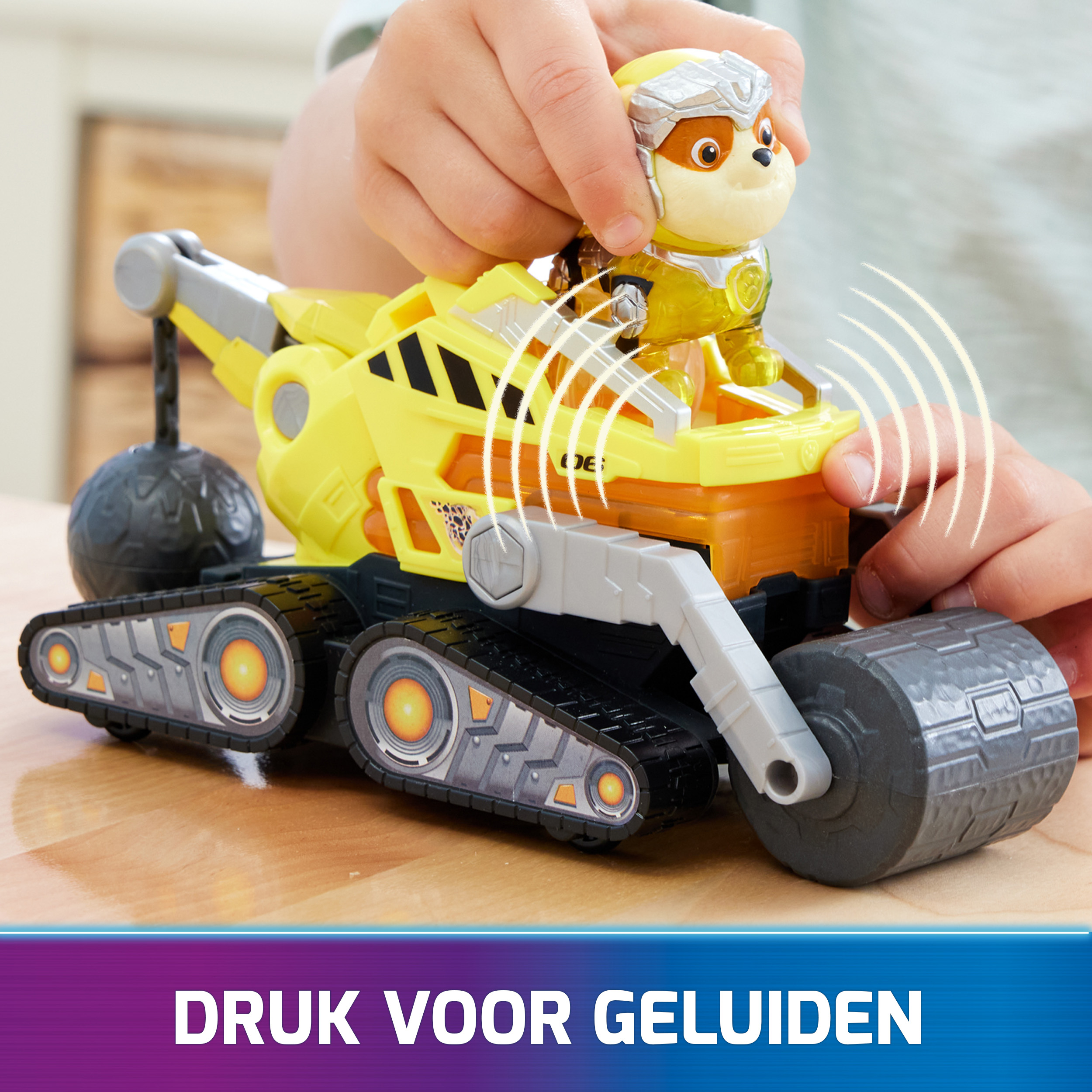 Gelber Spielzeug-Truck mit Hundefigur. Ein Kind hält das Spielzeug. Text: Drücken Sie für Geräusche.