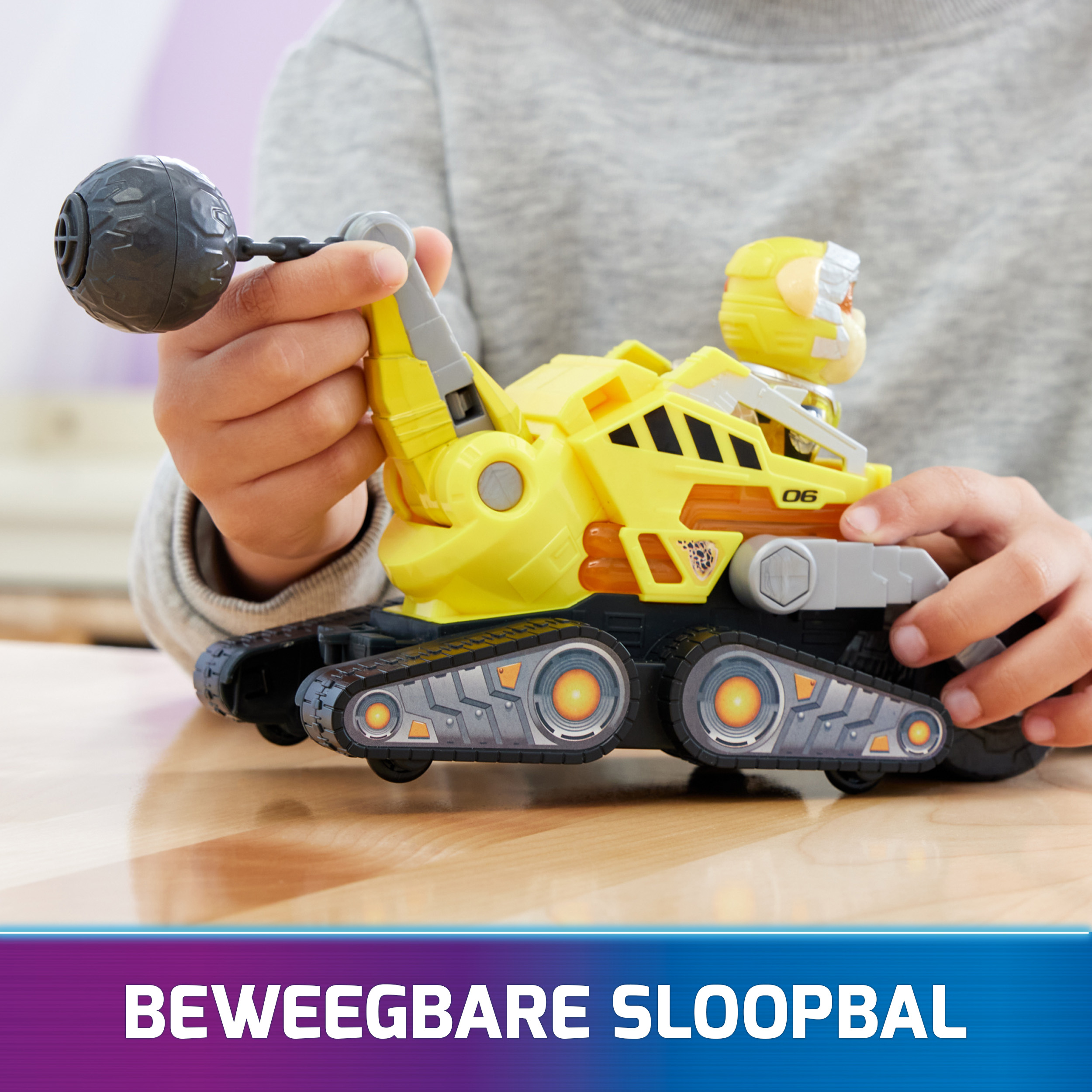 Ein Kind spielt mit einem gelben Spielzeugpanzer mit grauer Kugel.