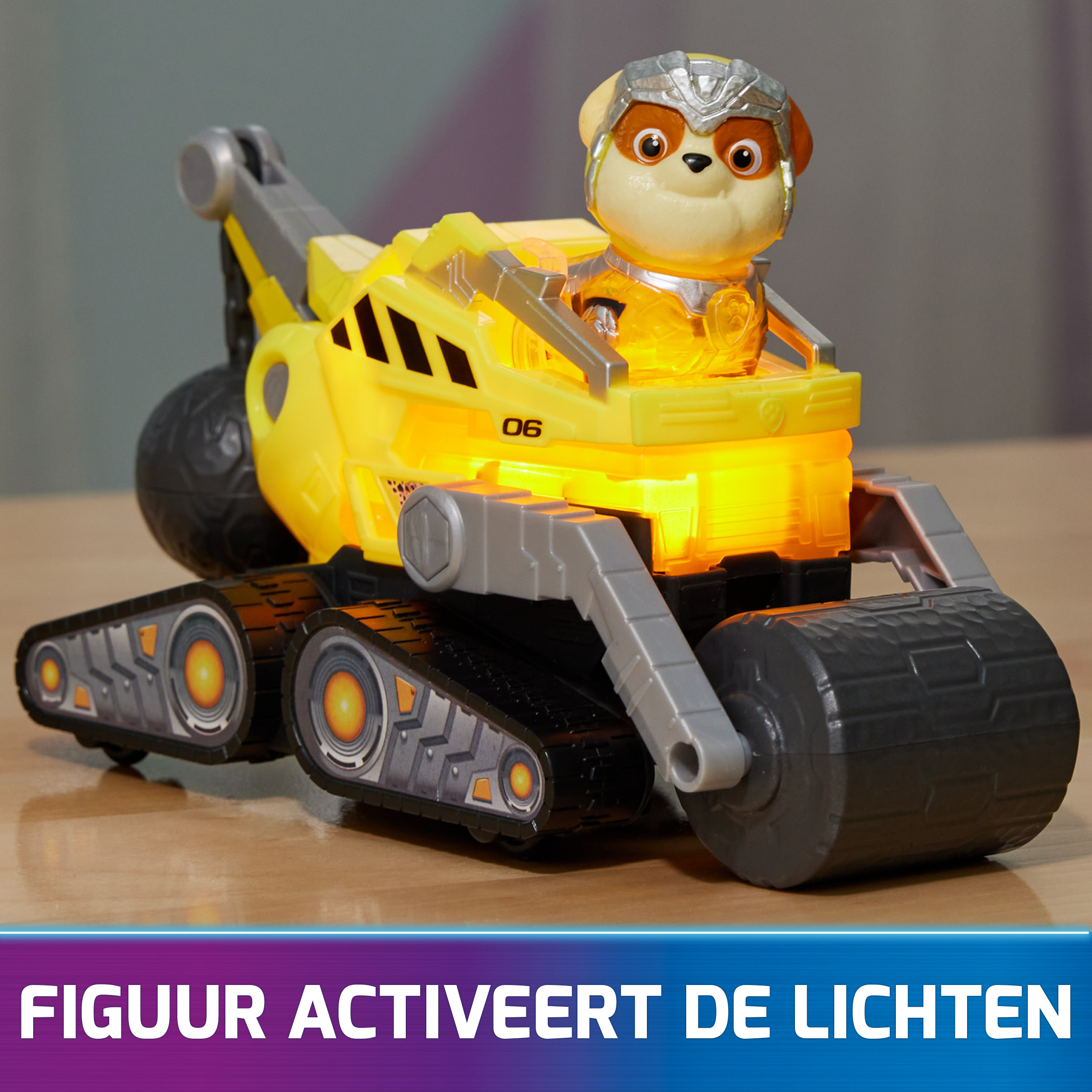 Gelber Spielzeug-Truck mit Hundefigur und leuchtenden Lichtern. Text: Figur aktiviert Lichter. Der Truck steht auf einem Tisch.