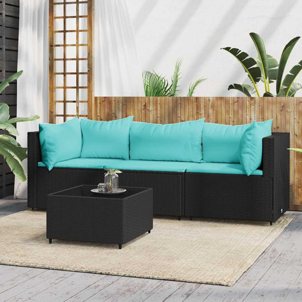 Schwarzes Outdoor-Sofaset mit türkisfarbenen Kissen und einem Couchtisch auf beigem Teppich.