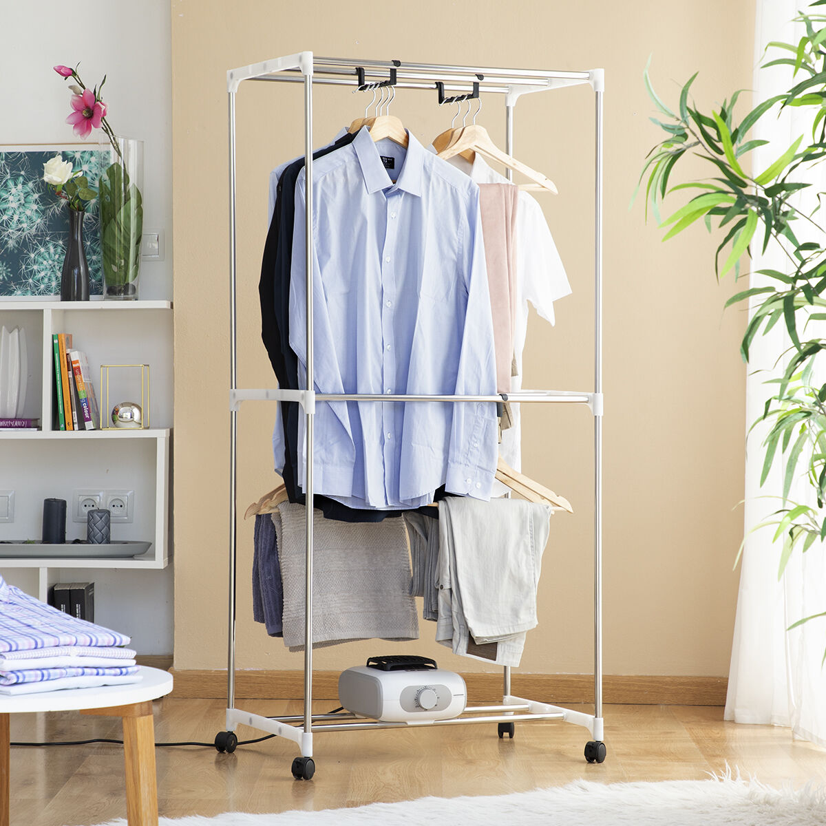 Un perchero metálico con camisas y pantalones. Debajo hay un pequeño electrodoméstico.