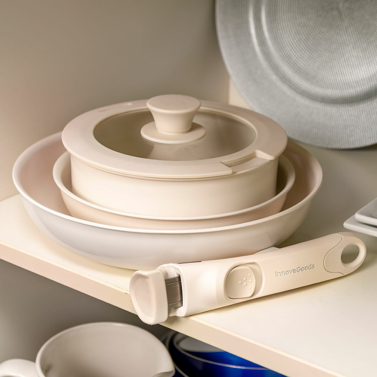 Stoviglie beige, tra cui ciotole e un coperchio, riposte su uno scaffale.