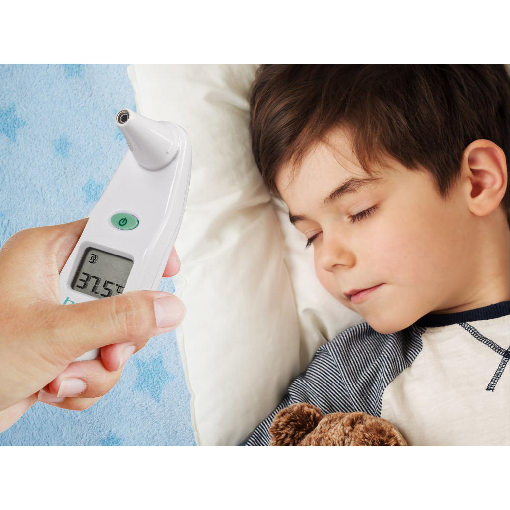 Una mano tiene un termometro auricolare digitale all'orecchio di un bambino addormentato, mostrando una lettura di 37,5°C.