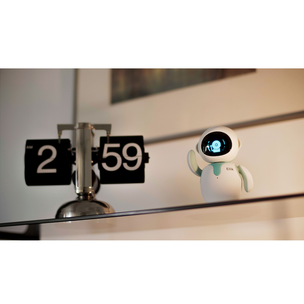 Ein weißer Roboter namens Eilik mit türkisfarbenen Akzenten auf einem Glasregal in der Nähe einer Uhr mit der Zeit 2:59 Uhr.