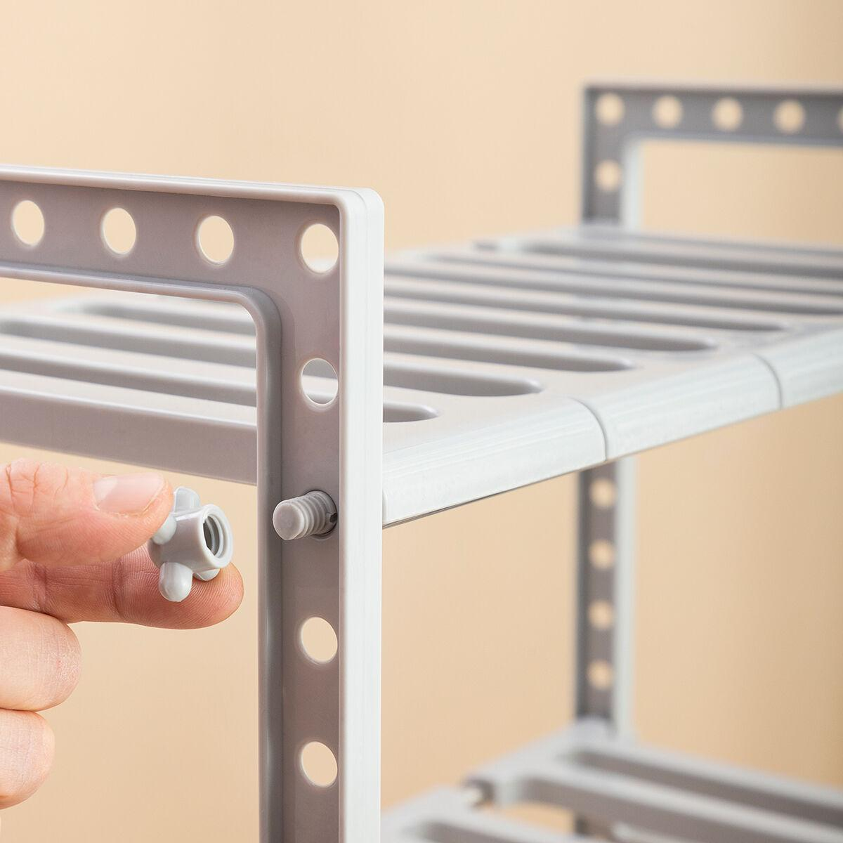 Una mano che tiene una vite per la costruzione dello scaffale grigio, primo piano.