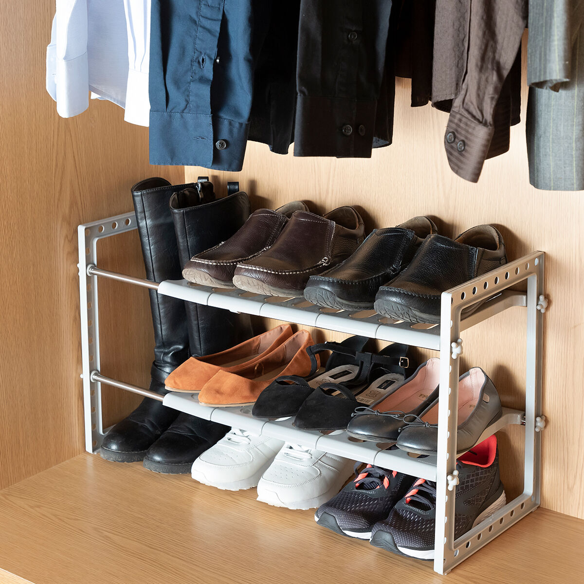 Una scarpiera con varie scarpe e stivali in un armadio. Include stivali e varie scarpe.