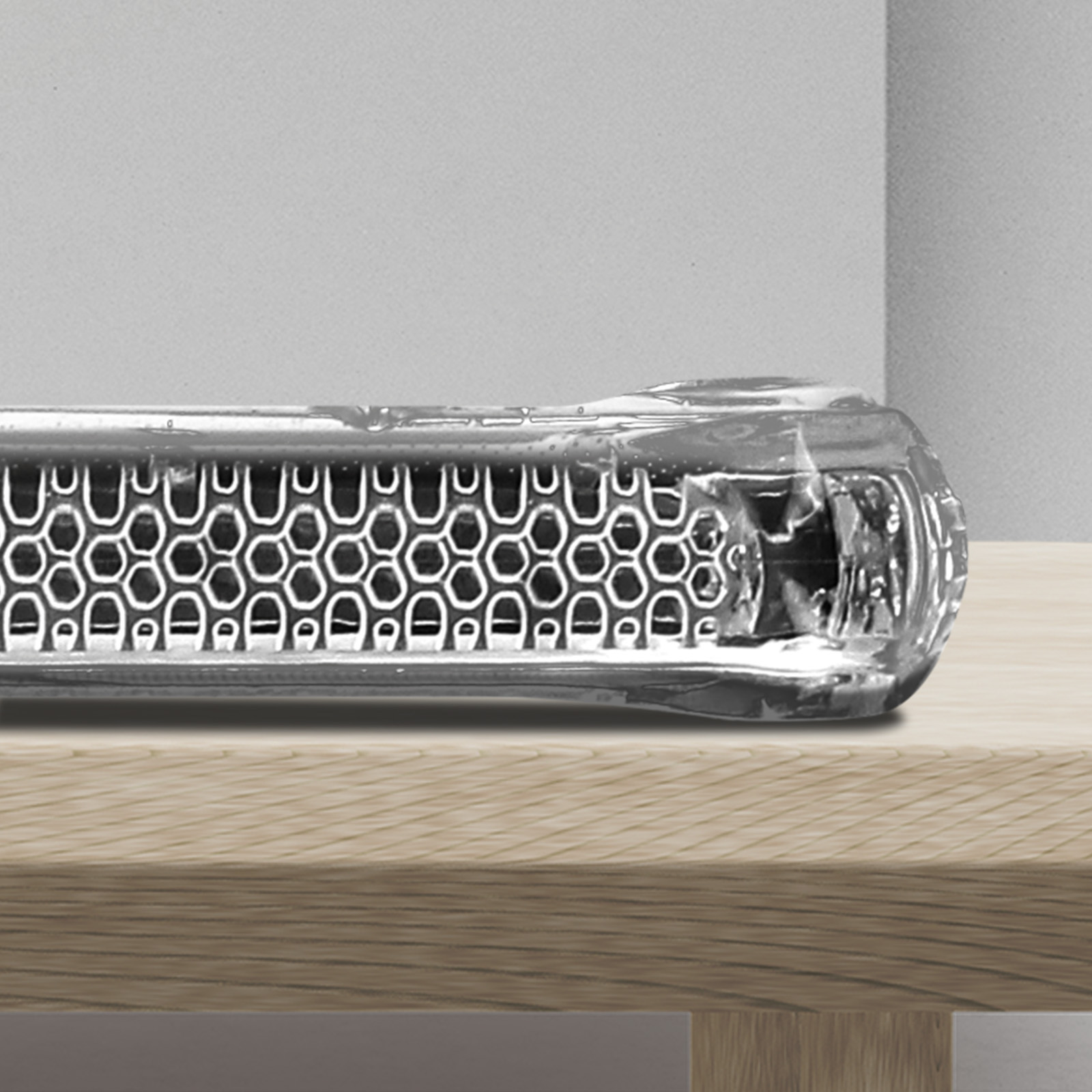 Primo piano di una custodia per telefono. La custodia è trasparente e poggia su una superficie di legno.