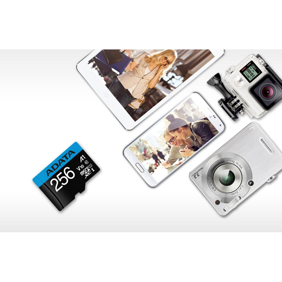 Różne urządzenia technologiczne: Tablet, telefon, aparat i karta SD. Przedmioty na białej powierzchni, skierowane w dół.