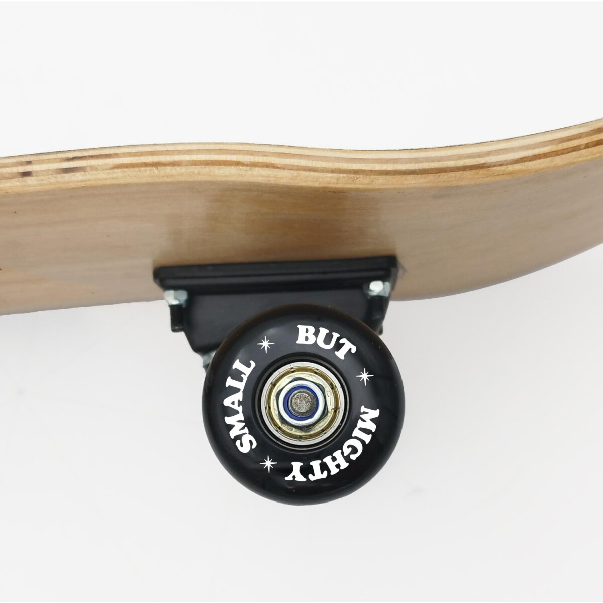 Nahaufnahme eines Skateboard-Rads mit den Worten 'SMALL BUT MIGHTY' und einem schwarzen Truck auf Weiß.