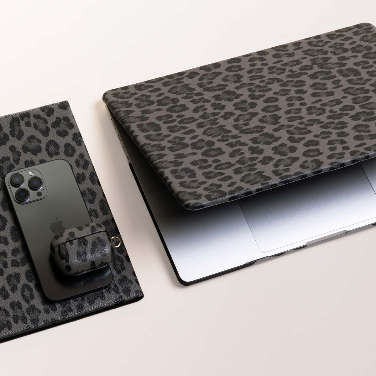 Laptop, phone, and accessories with gray leopard print.