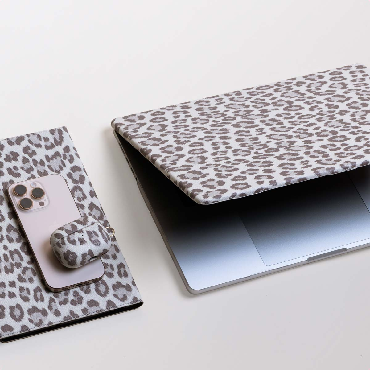 Laptop, phone, and case with leopard print, white background. Top view.