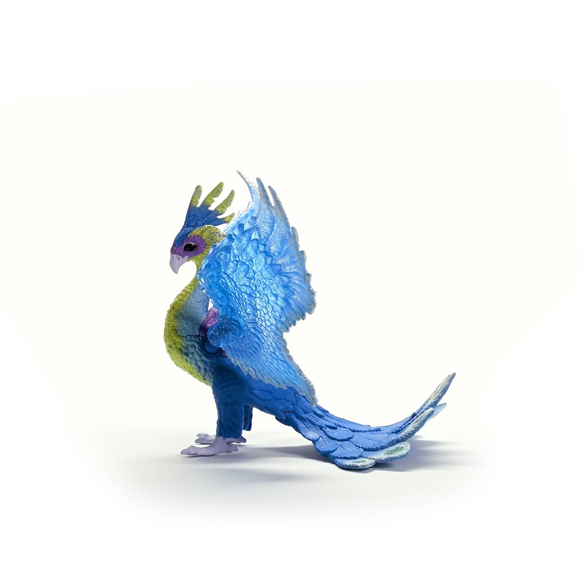 Un uccello fantasy blu e giallo, con le ali spiegate. Si trova su una superficie bianca. Sfondo bianco.