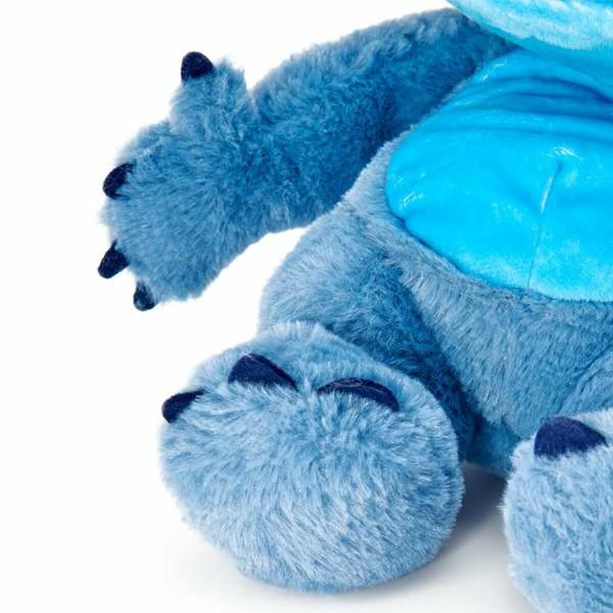 Primer plano del brazo y la pata de un monstruo de peluche azul.