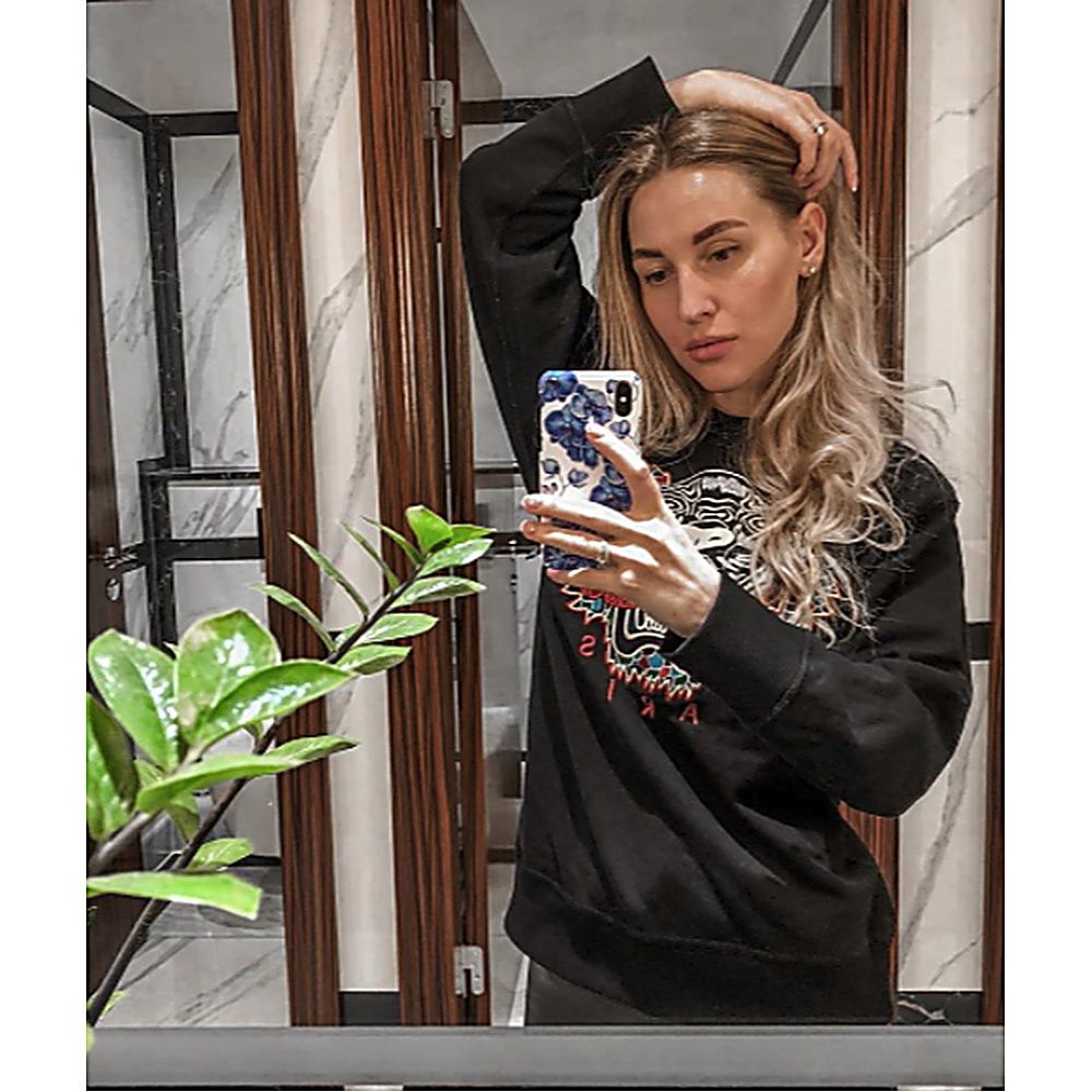 Donna che si fa un selfie allo specchio. Tiene un telefono con una custodia floreale.