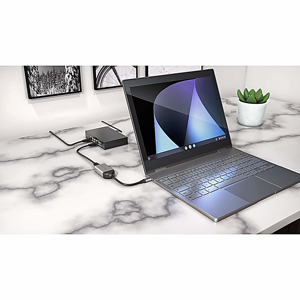 Una computadora portátil conectada a un concentrador y otros dispositivos. La computadora portátil está abierta en un escritorio.