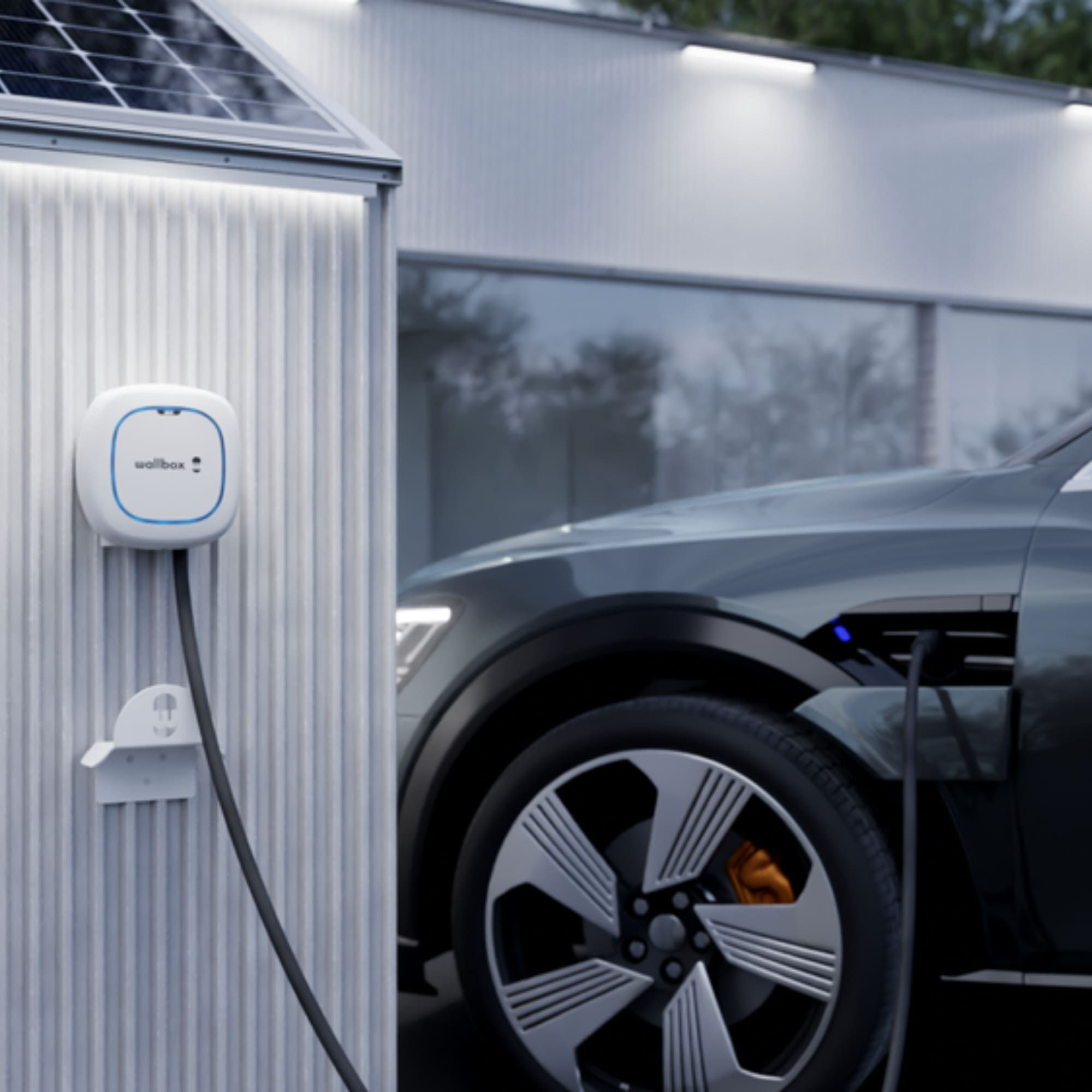 Ein Elektroauto lädt an einer Ladestation. Das Kabel ist mit dem Auto verbunden.