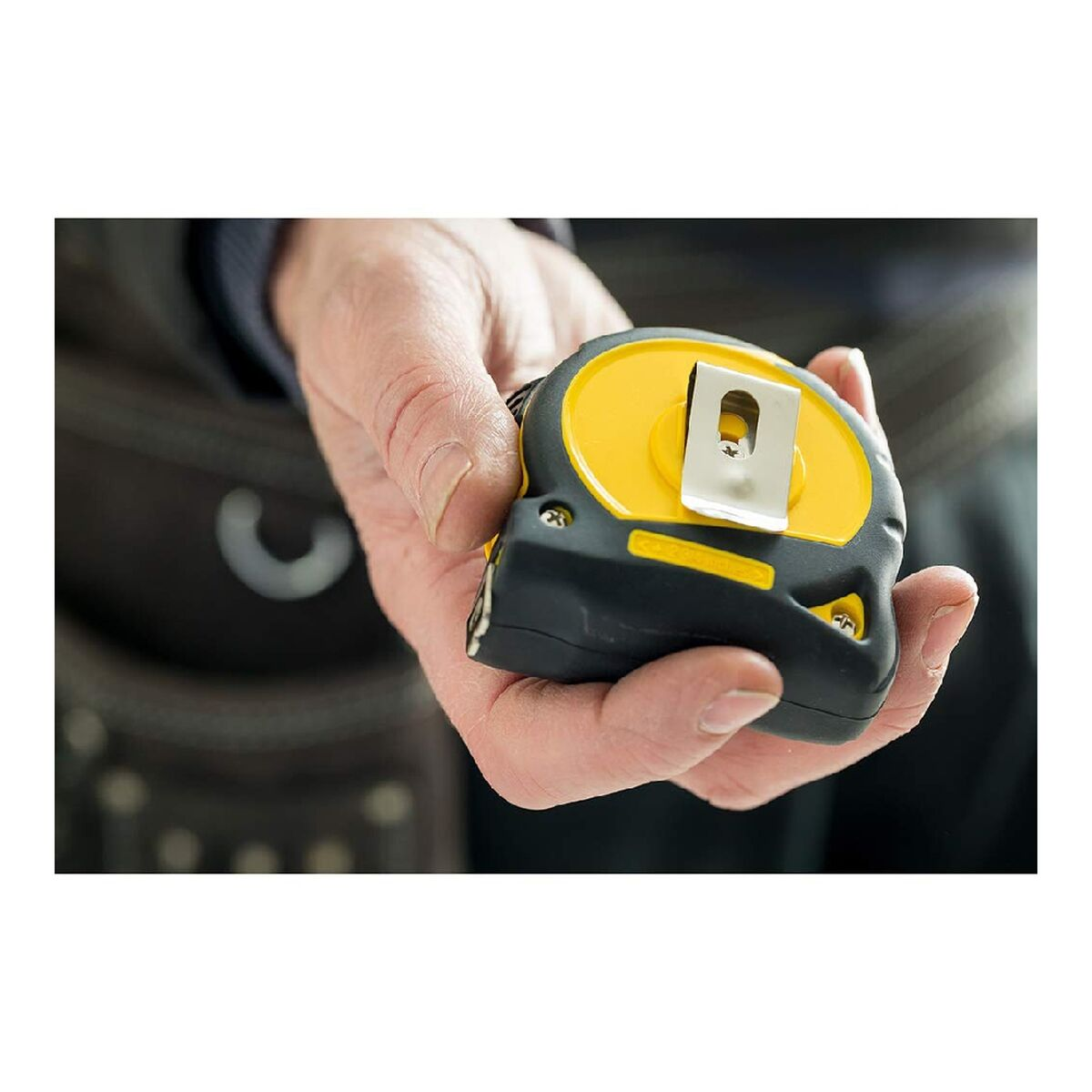 Ręka trzymająca żółto-czarną miarkę. Miarka jest używana.