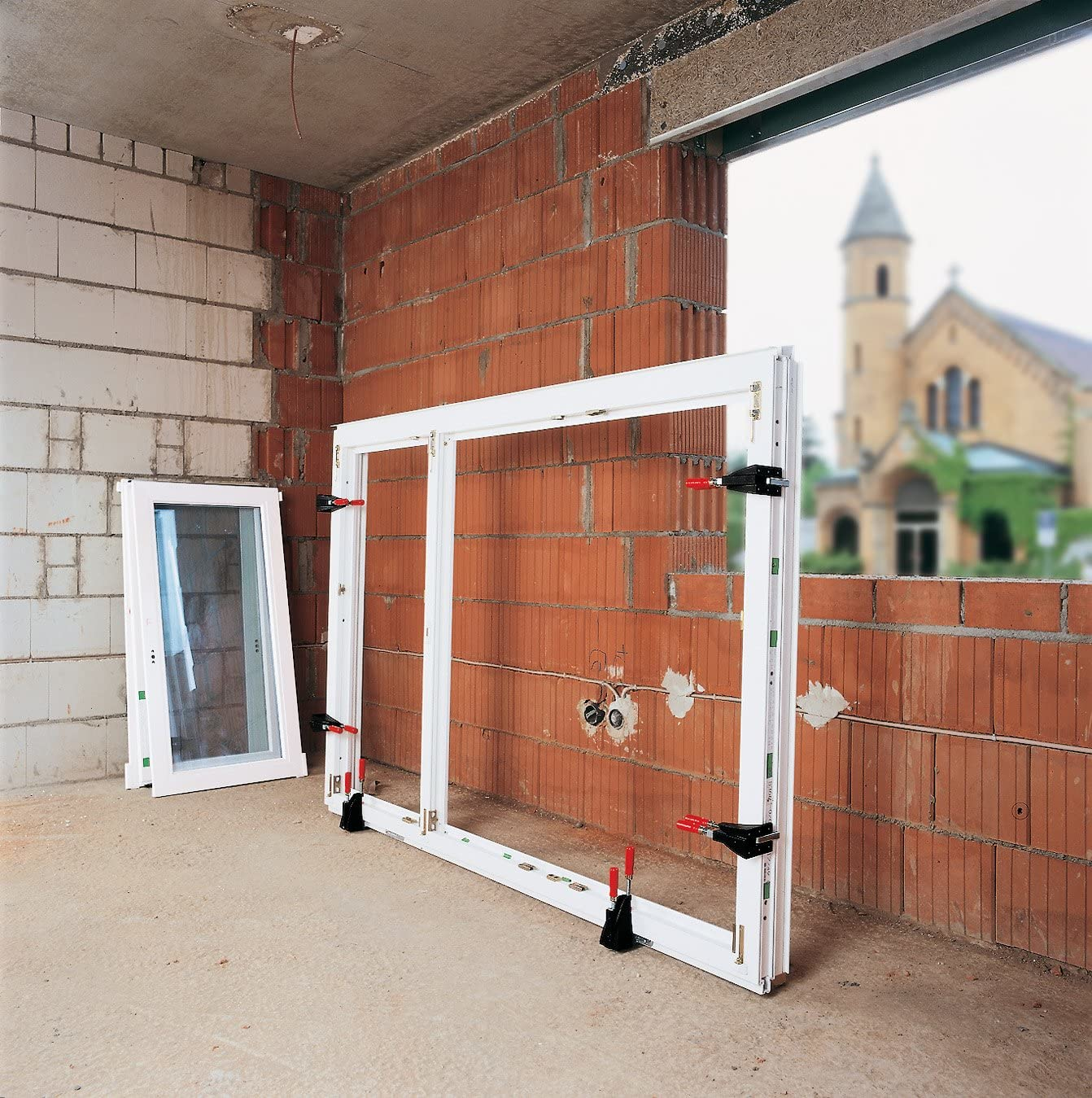 Baustelle. Fenster sind eingebaut. Im Hintergrund ist eine Kirche zu sehen.