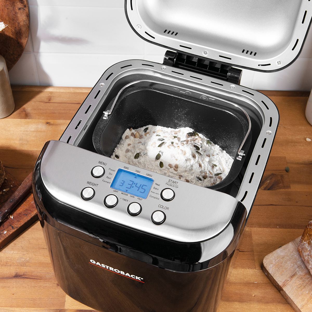 Innenraum des Brotbackautomaten mit Brotteig. Der Innenraum ist schwarz und der Deckel ist geöffnet.