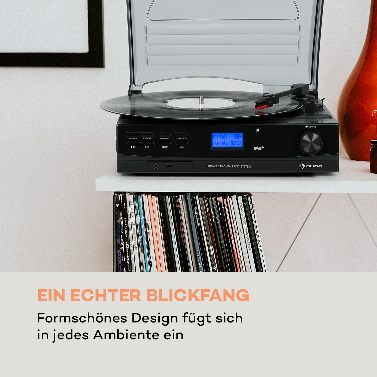Plattenspieler auf weißem Regal, mit Schallplatten darunter und einer Vase rechts.