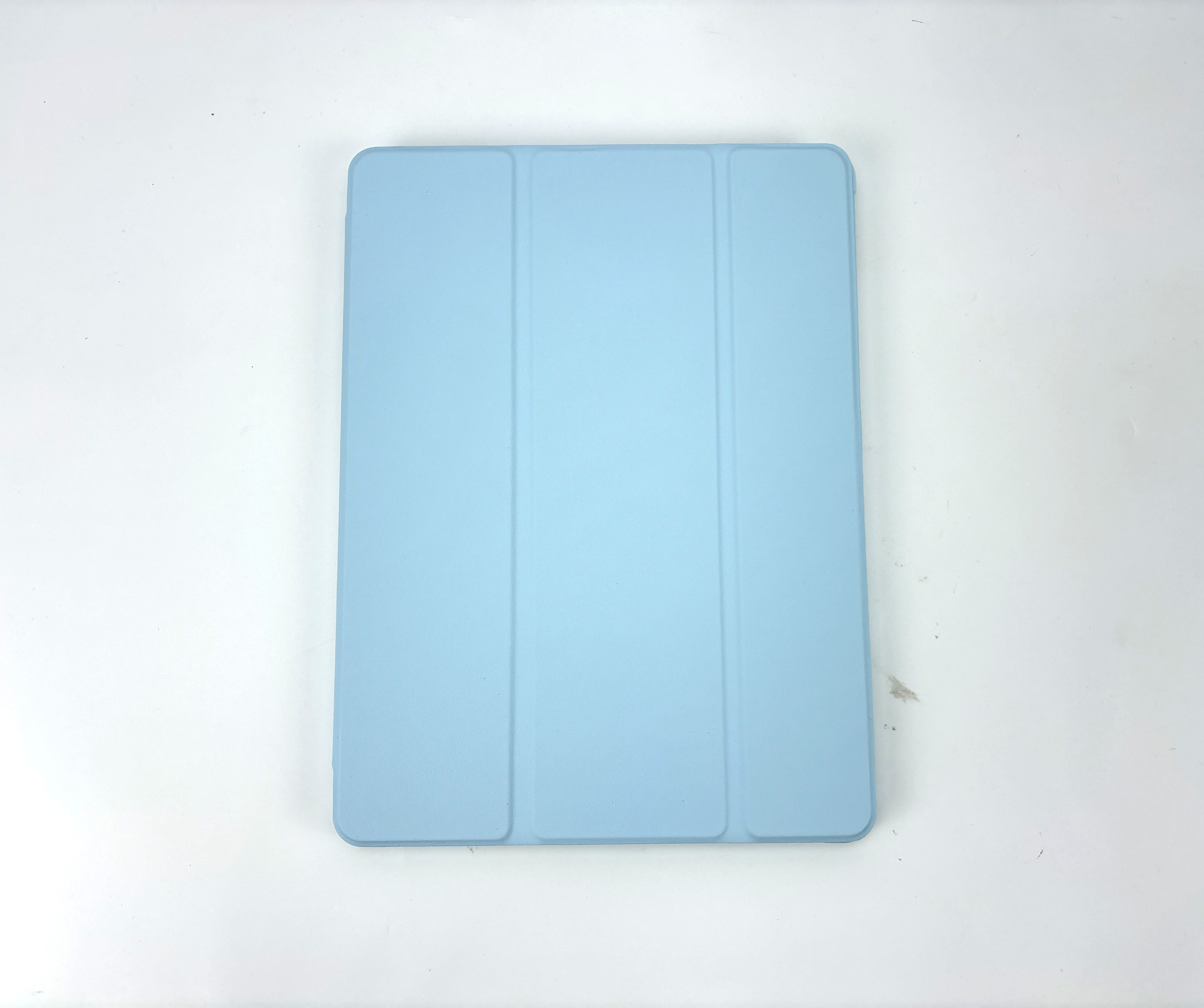 Een lichtblauwe iPad-hoes, gesloten, ligt op een wit oppervlak.