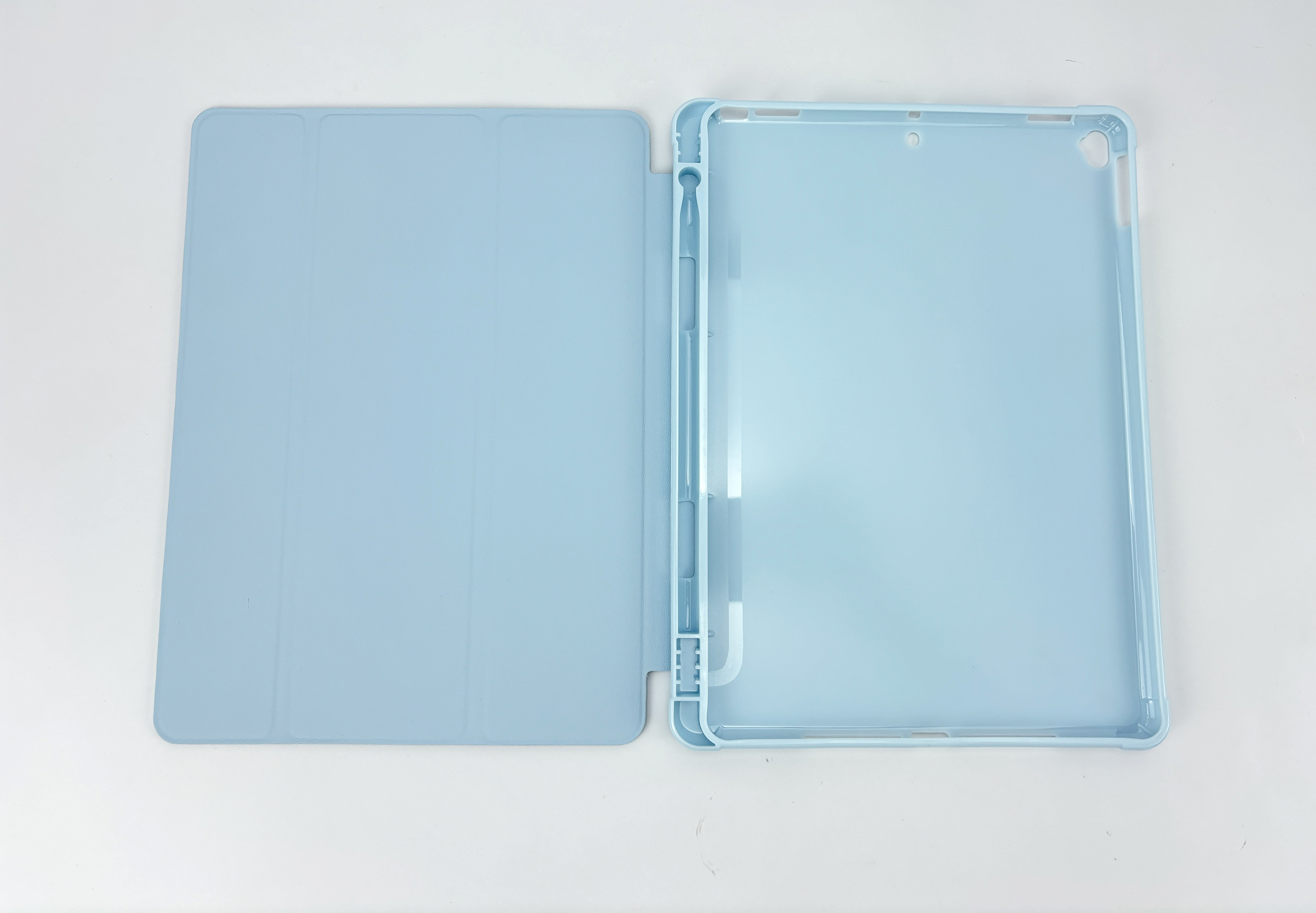 Een lichtblauwe iPad-hoes, open. De hoes ligt op een wit oppervlak.