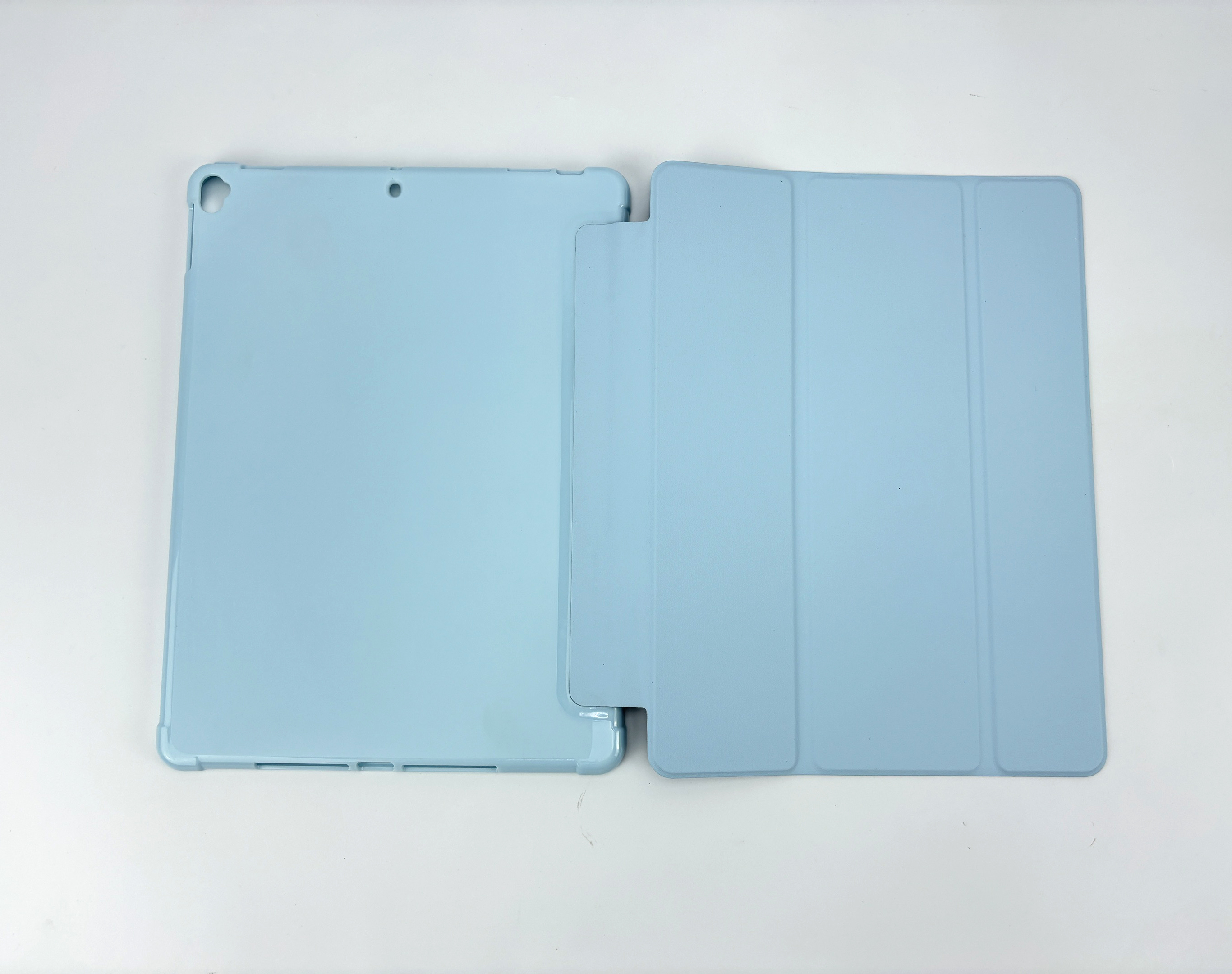 Een lichtblauwe iPad-hoes, open. De hoes ligt op een wit oppervlak.