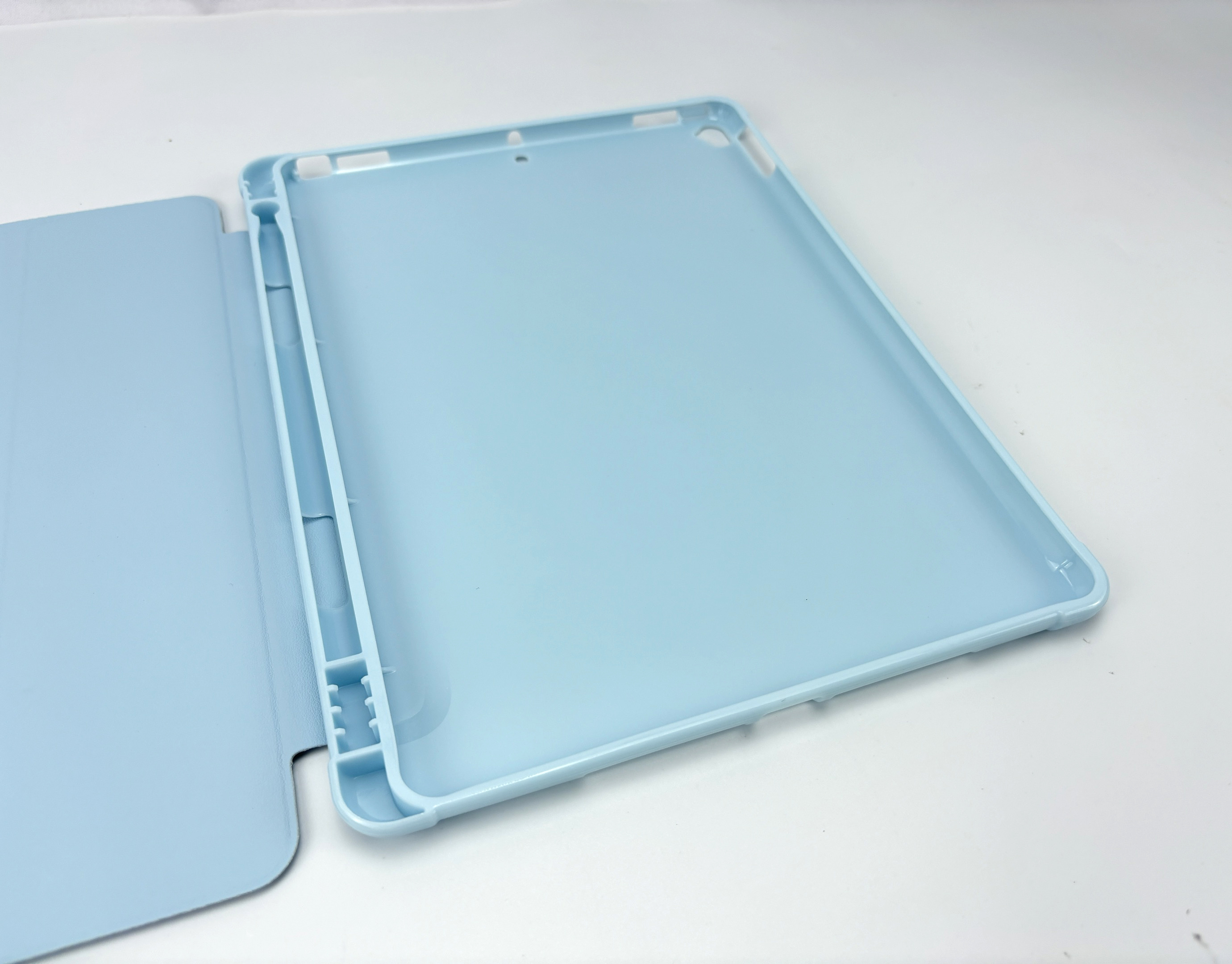 Een lichtblauwe iPad-hoes, open, waarbij de hoes gedeeltelijk de schermzijde bedekt.