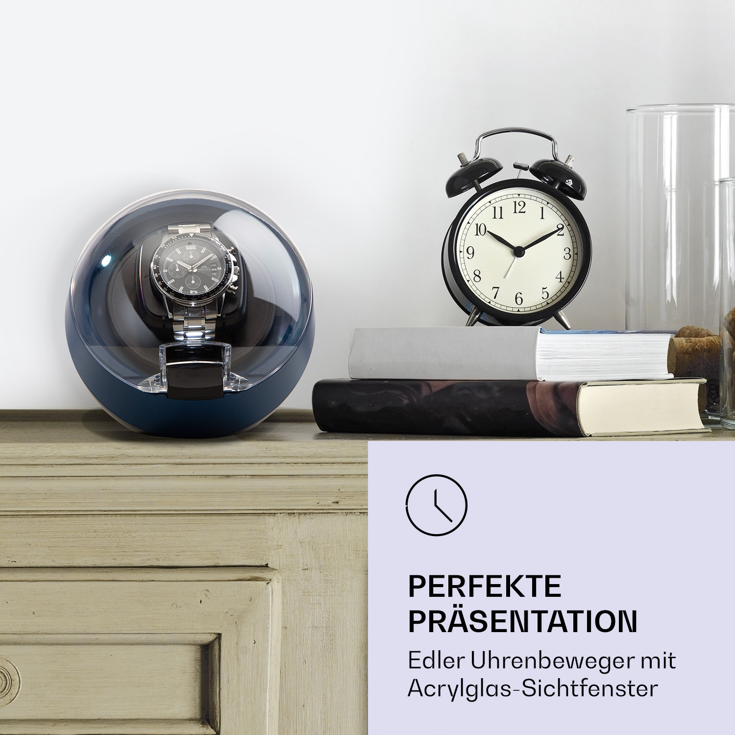 Uhrenbeweger, Wecker, Bücher und Glas. Text 'PERFEKTE PRÄSENTATION'.