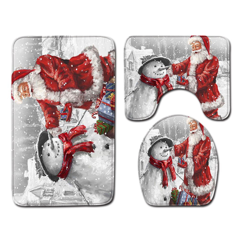 Drei festliche Badematten mit einem Schneemann- und Weihnachtsmann-Design. Die Matten befinden sich auf einem schneebedeckten Hintergrund.