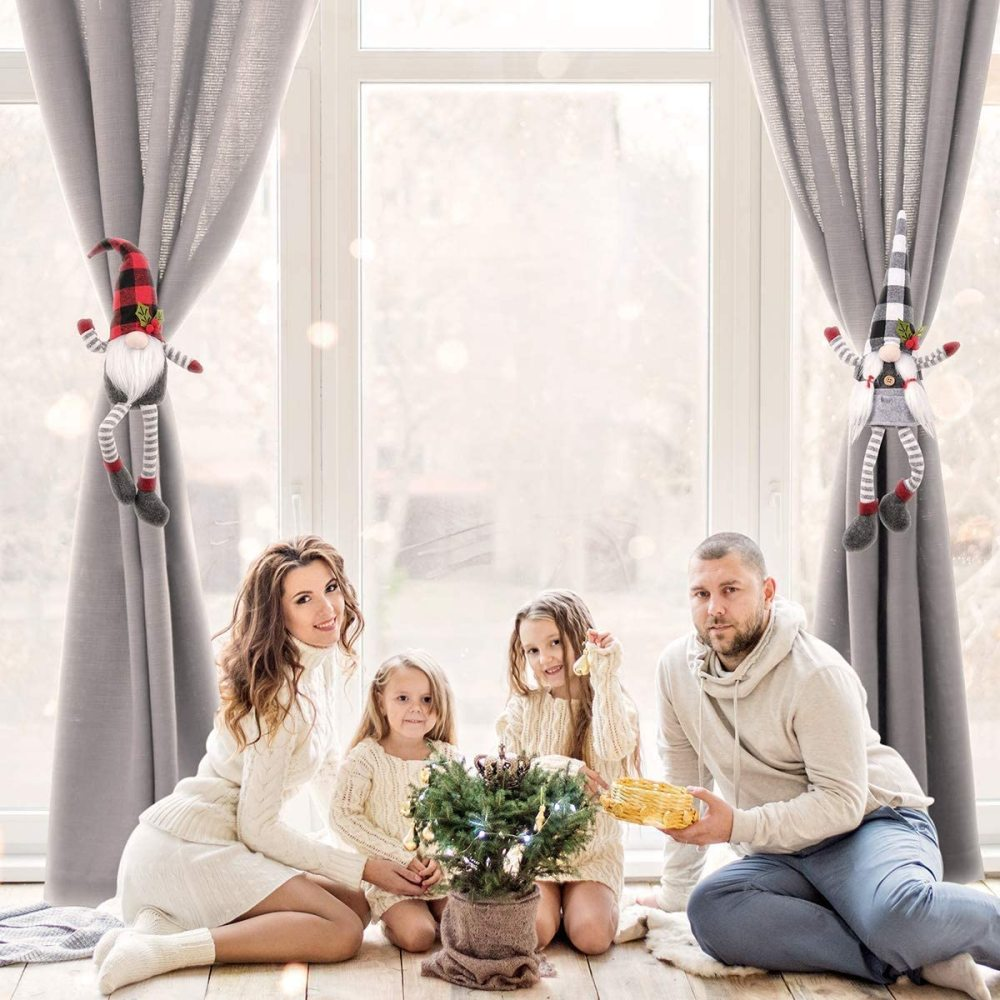Familie sitzt am Fenster mit Weihnachtsdekorationen. Die Familie besteht aus Eltern und zwei Kindern.