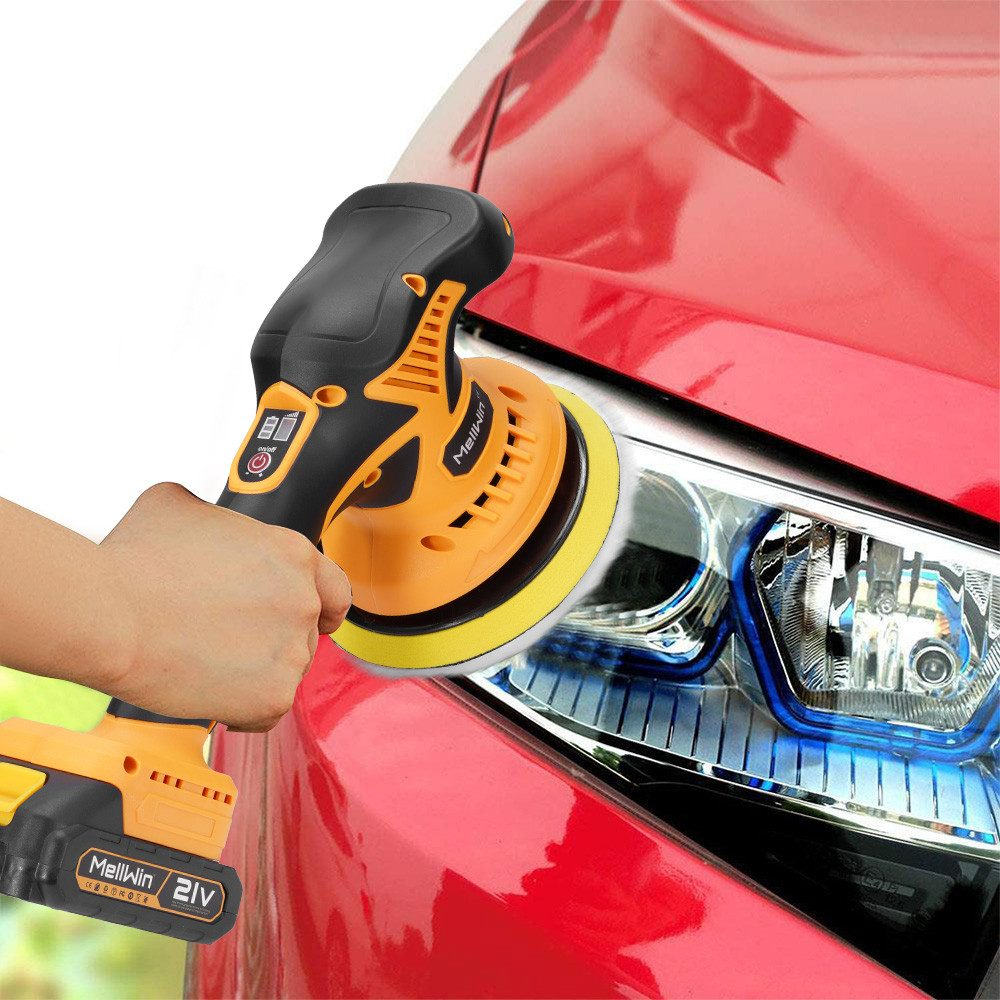 Eine Person, die ein rotes Auto mit einer orangefarbenen und schwarzen elektrischen Poliermaschine poliert. Zeigt Scheinwerfer.