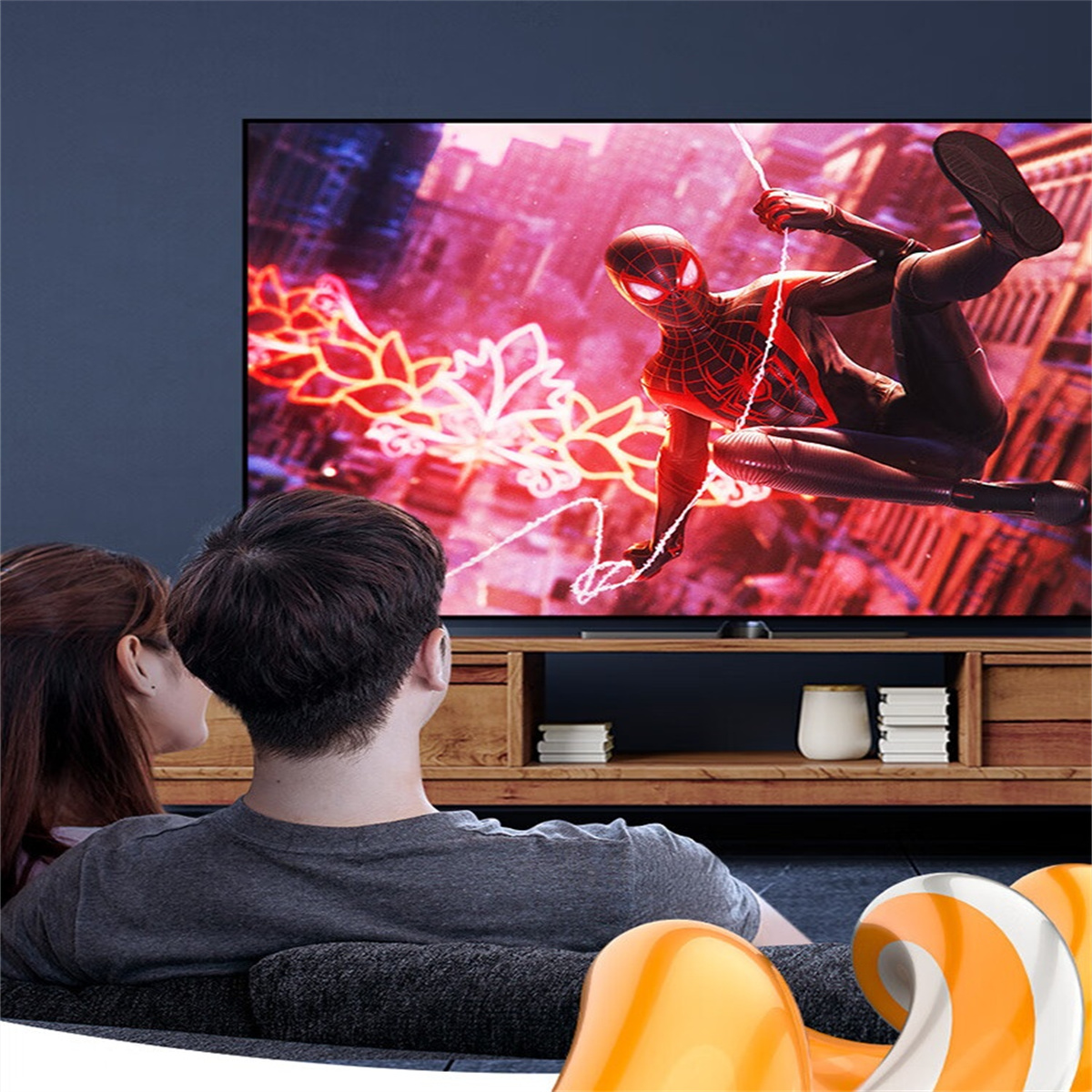 Zwei Personen schauen einen großen Fernseher mit einem Superhelden auf dem Bildschirm, auf einem Sofa sitzend.
