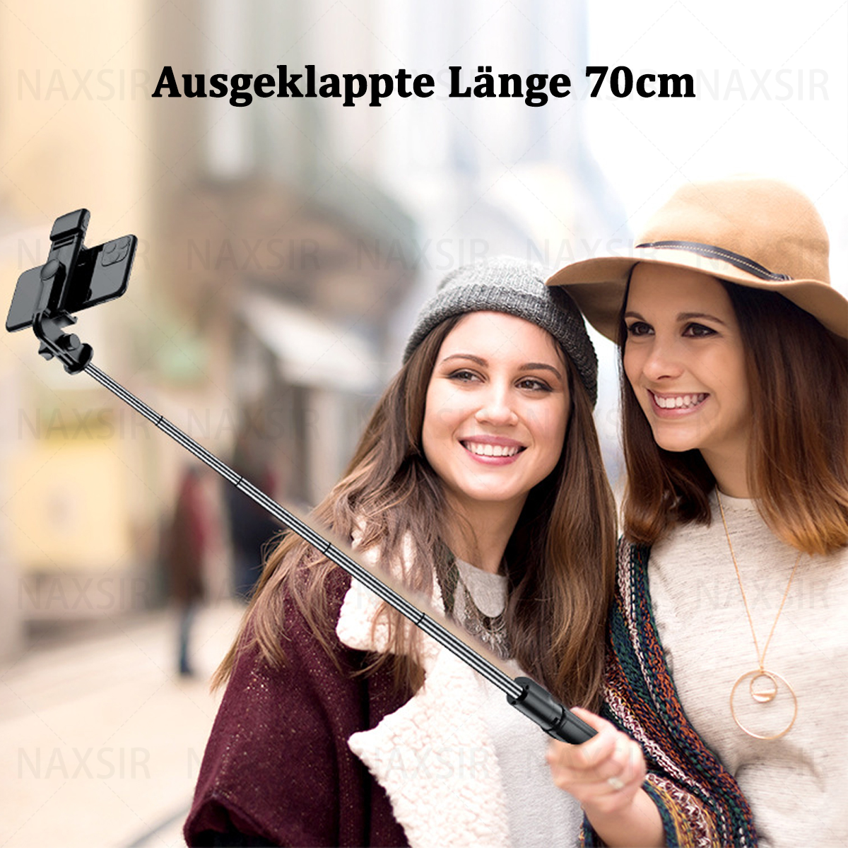 Zwei Frauen lächeln, benutzen einen Selfie-Stick. Verschwommener Hintergrund. Text: 'Ausgeklappte Länge 70cm'.