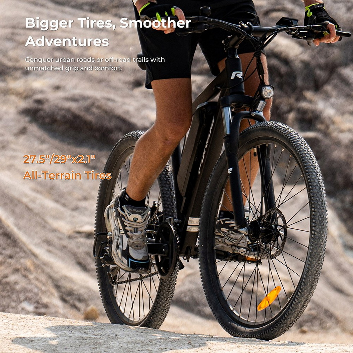 Rower elektryczny z dużymi oponami, prowadzony przez osobę, na skalistym terenie, tekst o oponach terenowych.