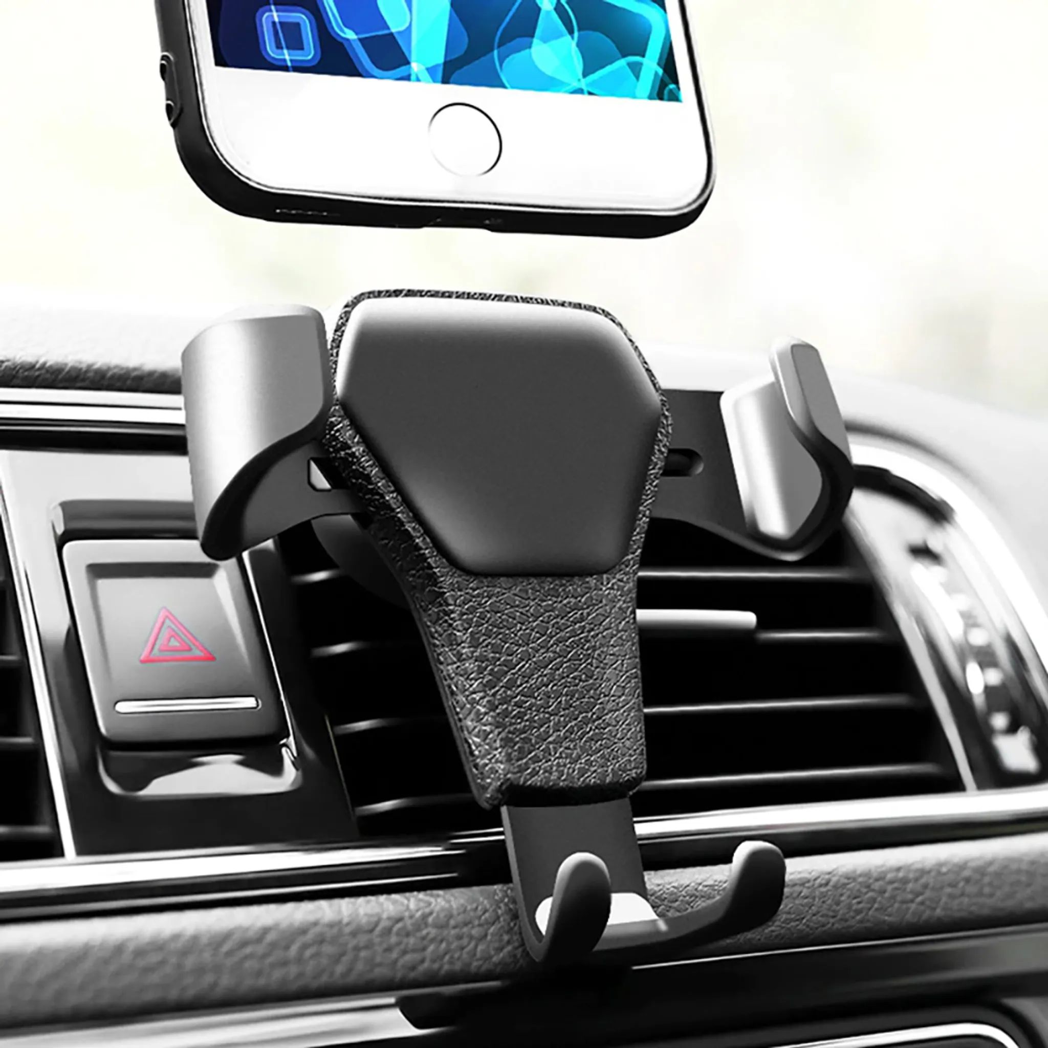 Schwarze Autotelefonhalterung, die ein Telefon hält. Das Telefon ist im Fokus, der Innenraum des Autos im Hintergrund.