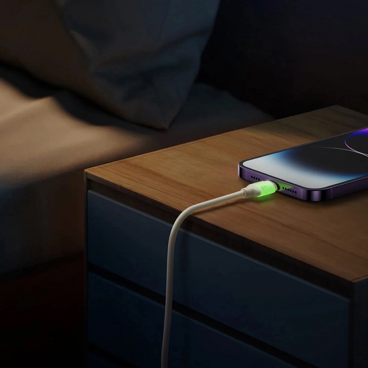 Un téléphone se chargeant sur une table de chevet avec un port de charge vert brillant.