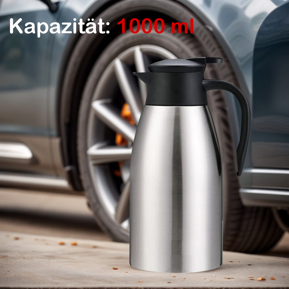Edelstahl-Thermoskanne mit schwarzem Deckel, auf Beton. Autoreifen im Hintergrund.
