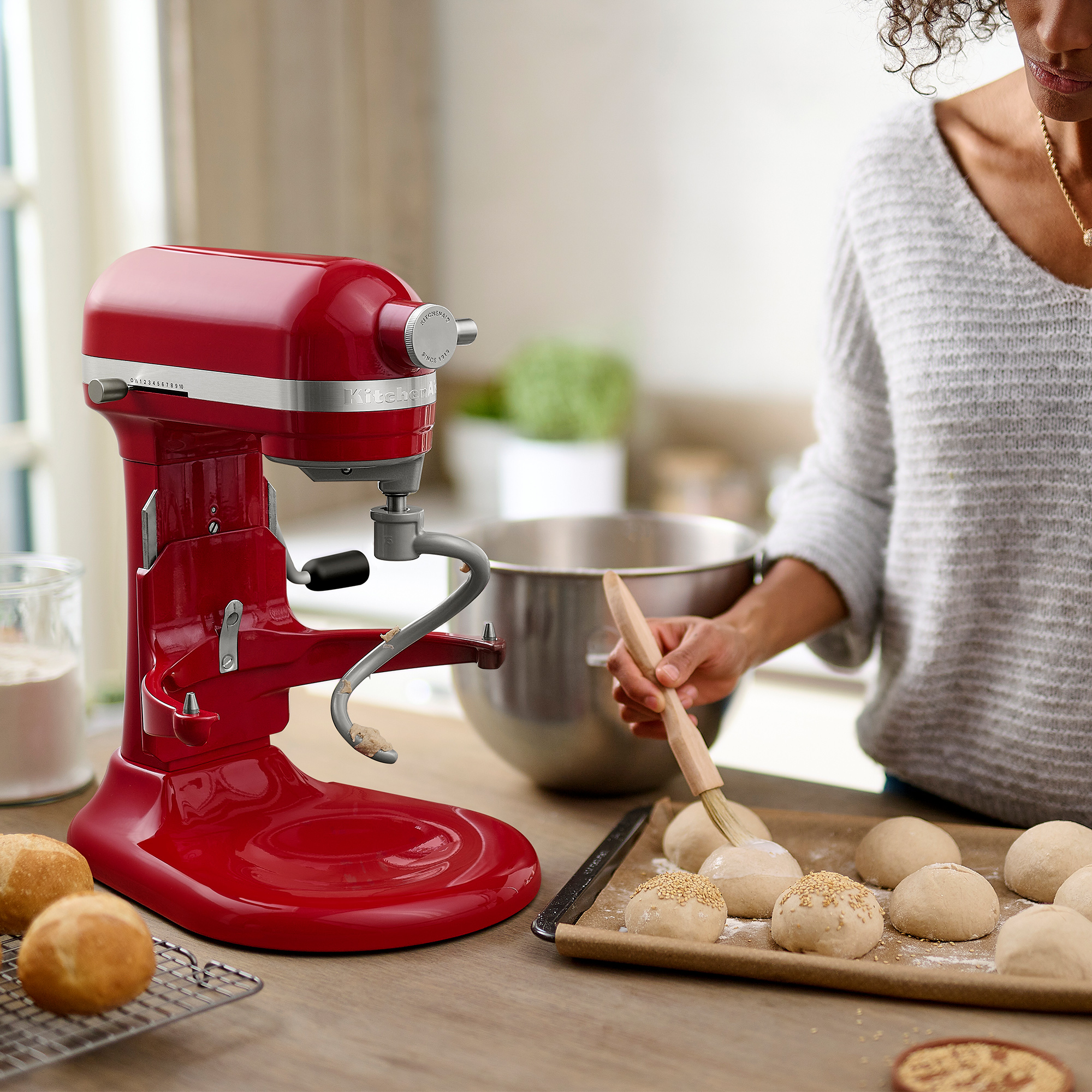 Un'impastatrice rossa con una donna che prepara l'impasto, ambiente cucina.