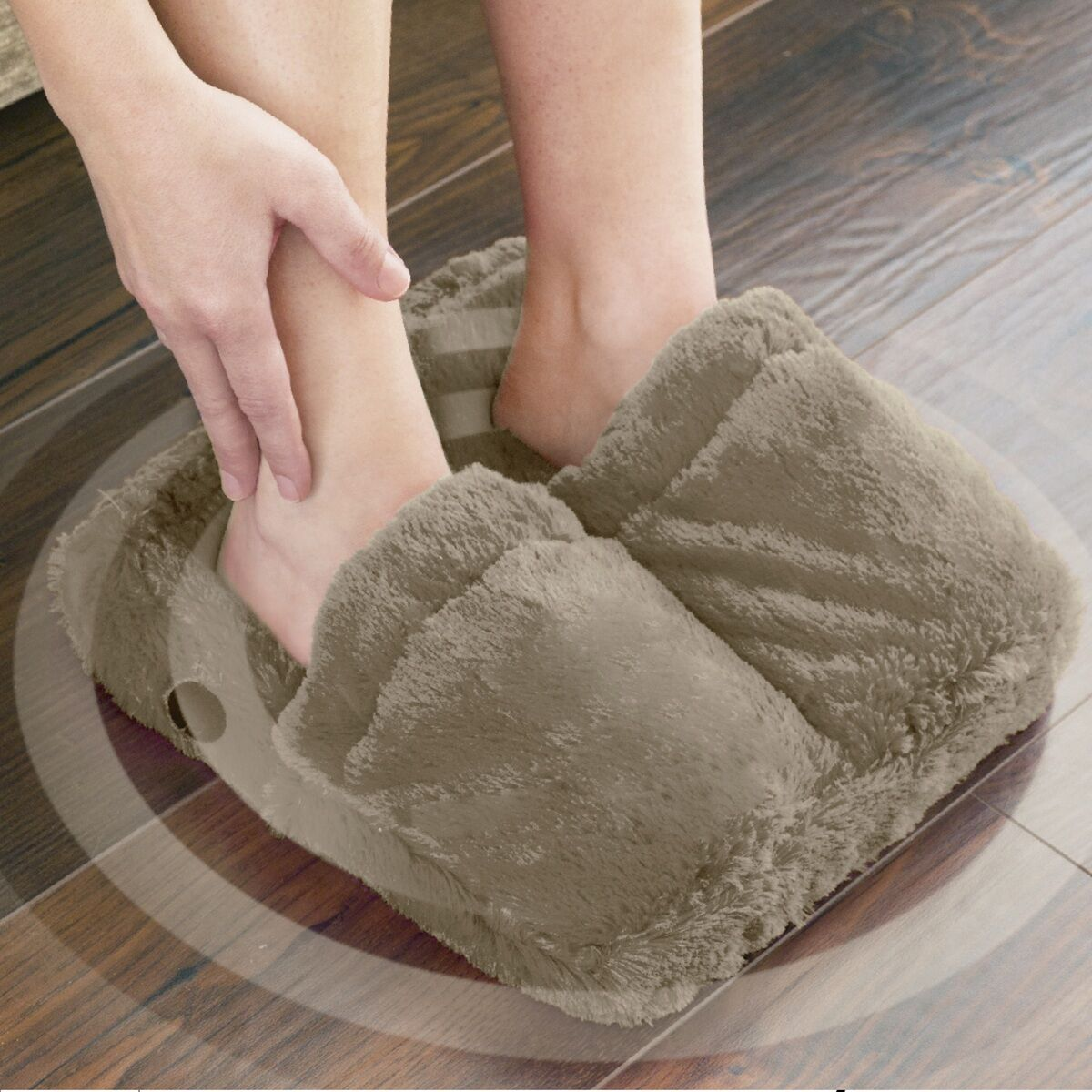 Pies en pantuflas térmicas marrones y esponjosas sobre un suelo de madera con diseño de baldosas.