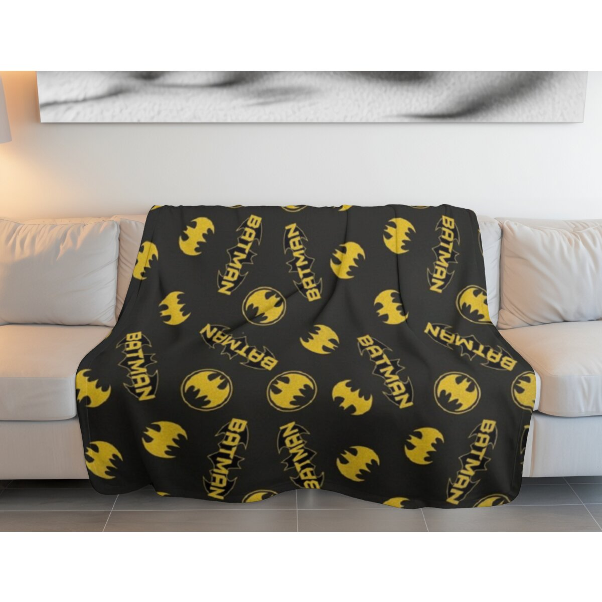 Batman-Decke auf einem weißen Sofa. Schwarze Decke mit gelben Batman-Logos.
