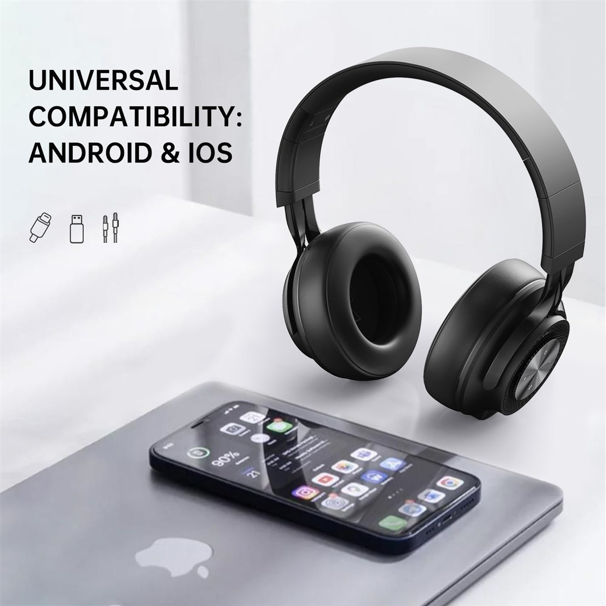 Schwarze Kopfhörer auf einem Laptop und Smartphone, die universelle Kompatibilität zeigen: Android & iOS.
