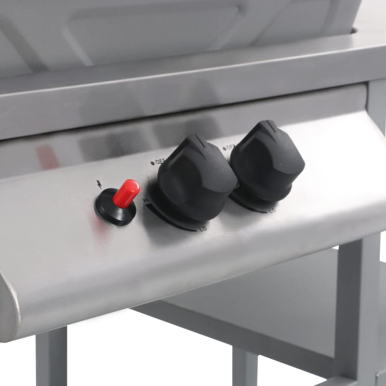 Nahaufnahme der Bedienelemente eines Grills. Zwei schwarze Knöpfe und ein roter Zündknopf sind sichtbar.