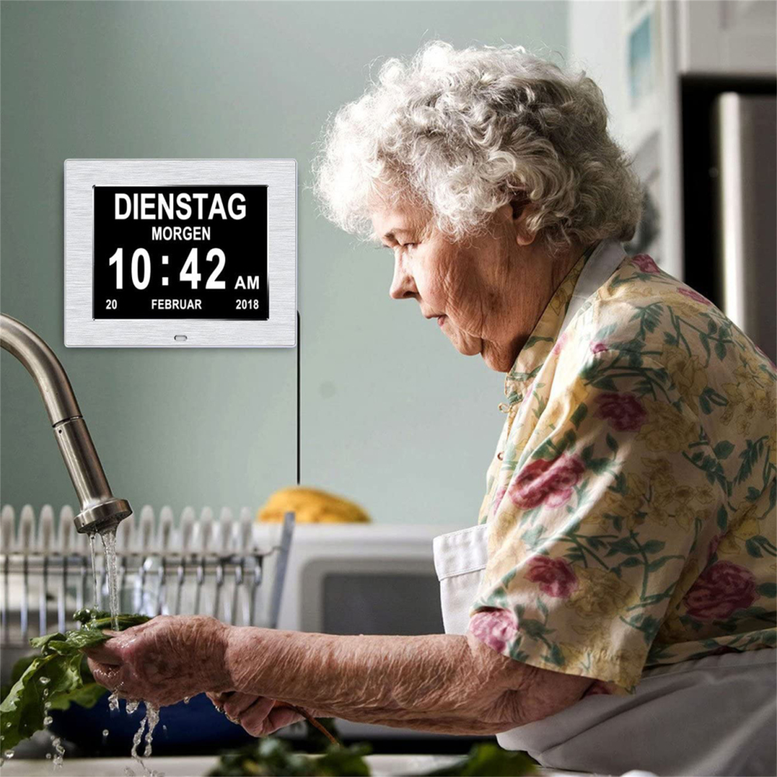Eine ältere Frau wäscht Gemüse in einem Waschbecken, mit einer Digitaluhr an der Wand.