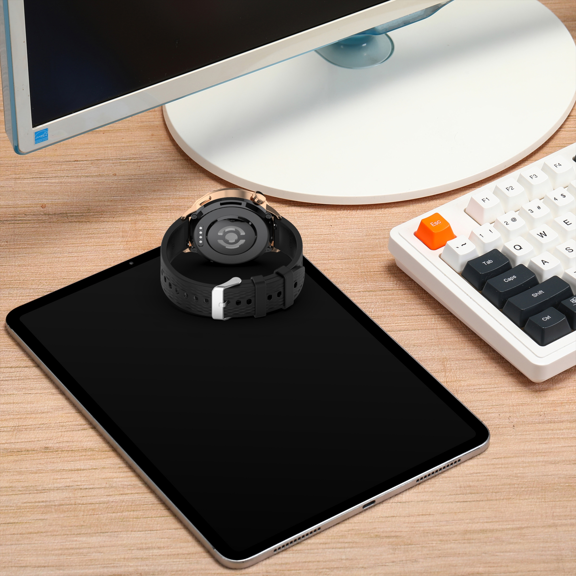 Smartwatch posizionato su tablet, tastiera e monitor.