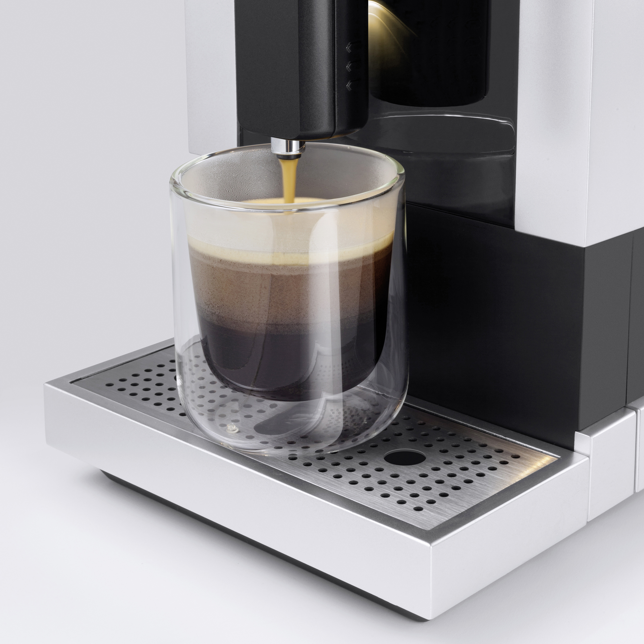 Kaffee wird in eine Glastasse ausgegeben.