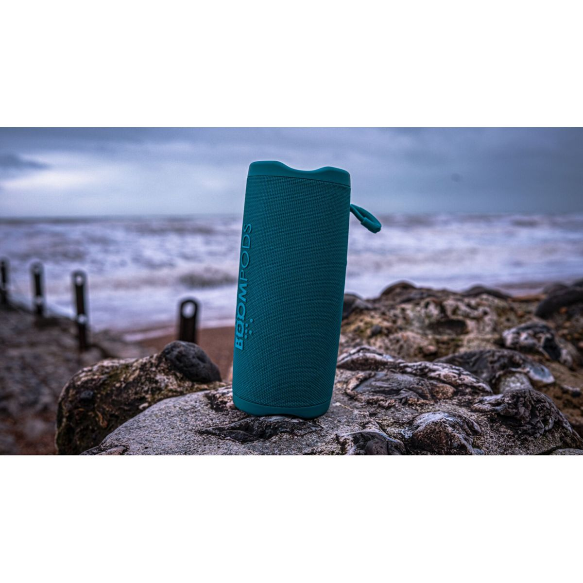Altoparlante verde acqua su rocce vicino all'oceano.
